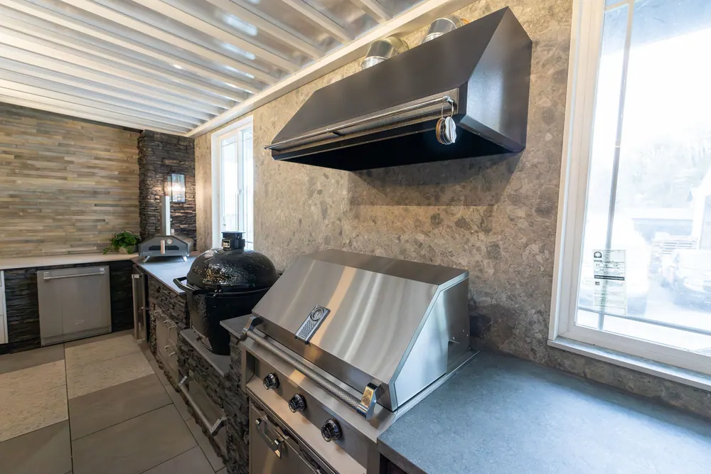 Outdoor kitchen with a built-in grill, vent hood and stone surround