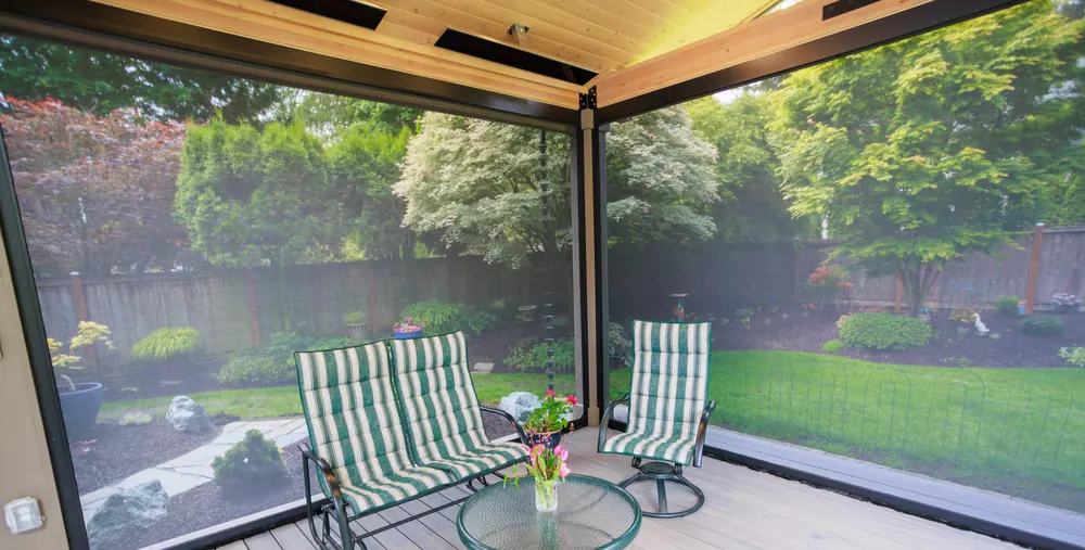 Motorized screen lowered across the open side of a covered patio